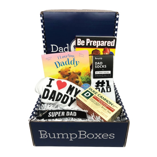 Dad box showing: I (heart) My Daddy white onesie, black keychain that says "Super Dad" in white, Duke Cannon Big American bourbon soap, pair of #1 dad socks, and a the "Be Prepared" practical handbook for new Dads, and  "I Love You Daddy" children's book